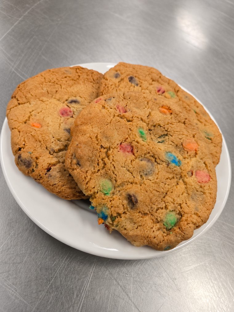 Large golden cookies studded with chocolate chips and colorful candy pieces on a white plate.